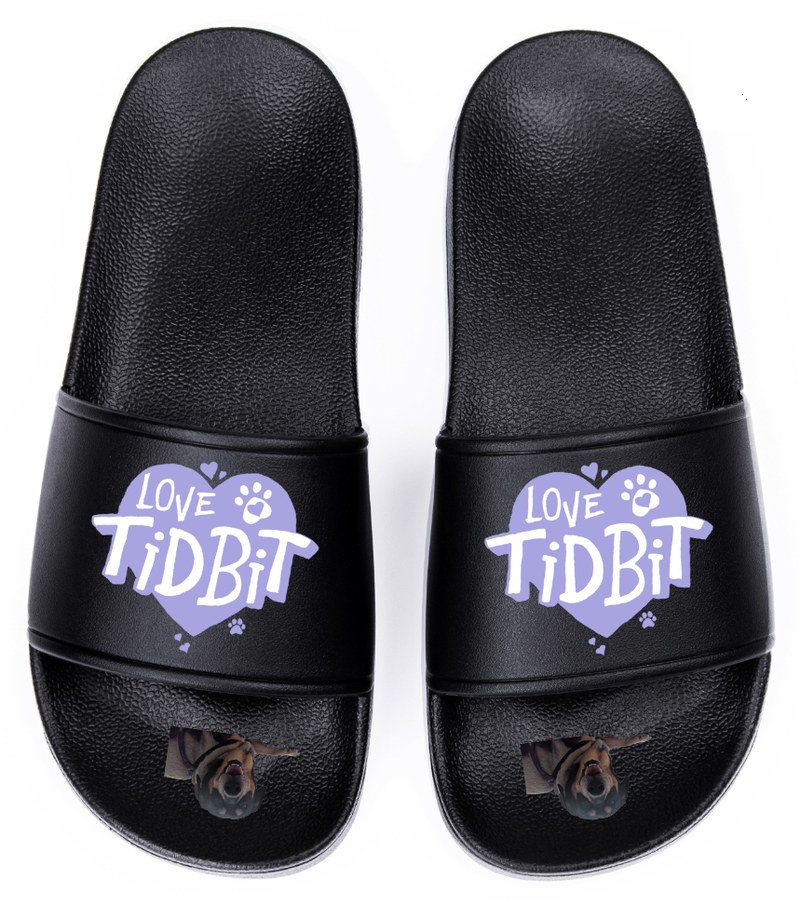 A pair of black Love Tidbit slides with the periwinkle heart logo on the strap and a photo of Tidbit on the footbed